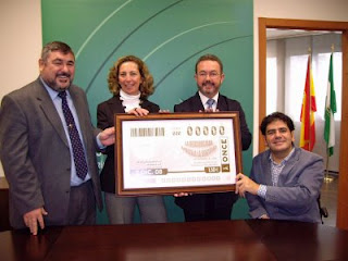 El presidente del Consejo sostiene la plancha del cupón del Día de la Discapacidad con el delegado de Igualdad en Sevilla