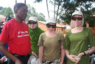 Tres jóvenes albinas con las gorras y las gafas que les han facilitado