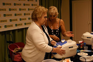 Una afiliada cocinando junto a la monitora en un momento de la presentación del robot de cocina