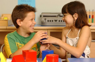 Dos alumnos disfrutan sonrientes probando el relieve de las figuras