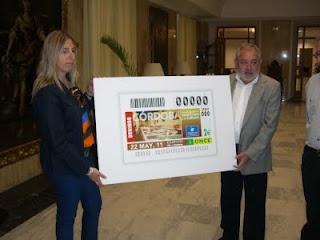 La nueva directora de la ONCE en Córdoba, Estela Medina, entrega una imagen del cupón al alcalde de la ciudad, Andrés Ocaña