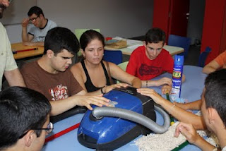 Varios estudiantes tocan una aspiradora para familiarizarse con ella