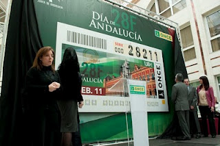 Griñán y Cárceles descubriendo la lona con la imagen del cupón dedicado al 28 de febrero