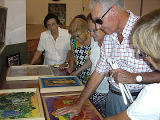 Varios afiliados tocando varios cuadros de la exposición