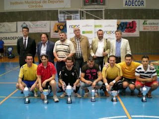 Los capitanes de los equipos ganadores posan en cuclillas con sus copas junto a las autoridades de pie