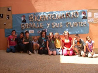 Los alumnos nazarenos sonrientes en el patio de su colegio bajo el cartel del Bicentenario de Luis Braille