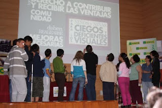 Alumnos de espaldas al público viendo el montaje audiovisual sobre el escenario
