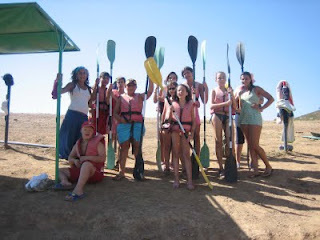 Todos los participantes con los remos en alto en la arena dispuestos a embarcar en sus piragüas