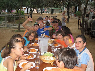 Chicos del campamento, sonrientes y amigables, sentados en una mesa durante una de las comidas