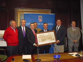 El director de la ONCE en Almería, Manuel Alborch, junto a los asistentes a la presentación del cupón de Canjáyar que posan con la copia de la plancha que dio origen al cupón