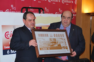 El director de la ONCE en Jaén, Pascual Gualda y el presidente de la Cámara de Comercio de Jaén, Antonio Sánchez sostienen la imagen del cupón del aniversario de la institución empresarial