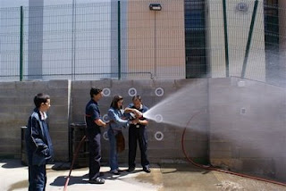 Dos jóvenes comprueban el funcionamiento de una manguera de bomberos