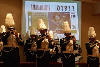 La Banda de la Banda de Cornetas y Tambores del Real Cuerpo de Bomberos de Málaga interpretando una marcha con la imagen del cupón proyectada al fondo