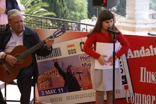 La niña Rachel Farahat, durante la lectura de la letra de 'Santa Lucía', acompañada por el guitarrista y afiliado, Paco Acosta