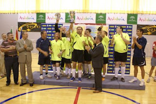 El equipo malagueñop alza su copa tras recibirla de manos del delegado de Igualdad en Sevilla