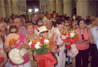 La vicepresidenta del Consejo Territorial, Amparo Cruz, junto a otras afiliadas, lleva un ramo de flores para depositarlo ante la virgen