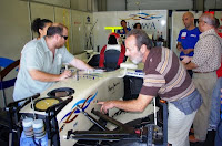 Un grupo de afiliados observan el coche de carreras minuciosamente