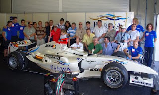 Foto de familia de los afiliados a la ONCE alrededor de uno de los coches de competición GP2