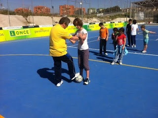 Asistentes al taller de fútbol en el campo de juego, mientras un coordinador les explica cómo deben colocarse