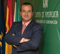 Primer plano de Higinio Almagro con las banderas de Andalucía y España de fondo