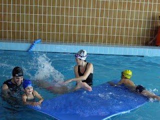 Varios pequeños, con sus monitores, disfrutando de una actividad en la piscina