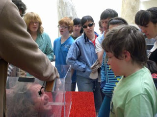 Escena de la dramatización teatral que acompañó la visita guiada al museo con una cabeza parlante dentro de una urna, ante el asombro de los chavales