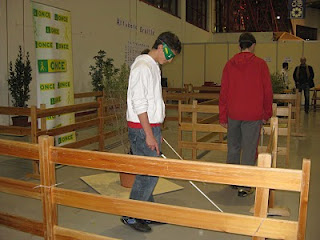 un joven participante realiza el circuito de barreras con un antifaz y un bastón