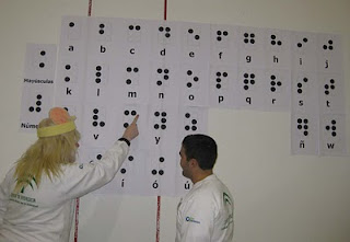 uno de los monitores enseña a un participante el alfabeto braille gigante