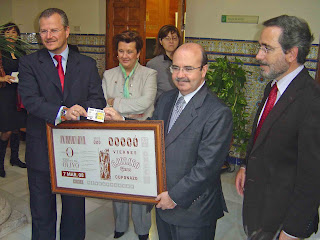 El delegado territorial y el consejero de la Presidencia enseñan a los periodistas gráficos la imagen del cupón Tierras del Olivo