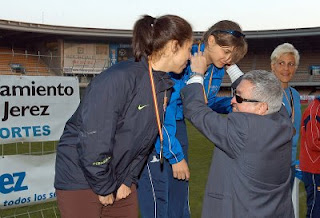 El director de la ONCE en Jerez, Ramón Zambruno, cuelga su medalla a una de las atletas ganadoras