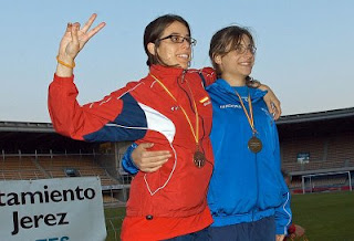 Dos atletas abrazadas con el símbolo de la victoria tras recibir la medalla