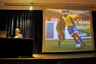 Un momento de la presentación del libro con una pantalla al fondo que visualiza imágenes de fútbol-sala
