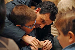 Primer plano de un niño tocando una de las piezas y recibiendo las explicaciones del guía