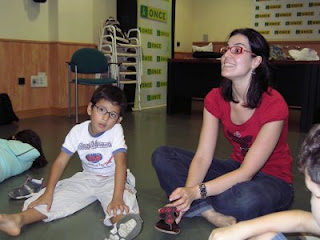 Un niño sentado de piernas abiertas escucha la música junto a su monitora