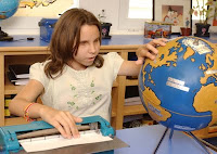 Una alumna observa el mapamundi en relieve mientras repasa en braille sus apuntes