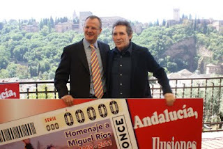 El rockero Miguel Ríos posa junto al delegado de la ONCE en Andalucía, Patricio Cárceles, y el cartel en el que aparece el cupón dedicado a su persona
