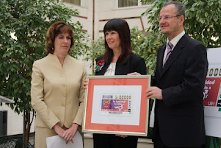 La directora del Centro de Recursos Educativos de la ONCE en Sevilla, Amparo Cruz, la consejera para la Igualdad y Bienestar Social de la Junta, Micaela Navarro y el delegado territorial de la ONCE en Andalucía, Ceuta y Melilla, Patricio Cárceles, sujetan la imagen del cupón del Día Internacional de la Mujer