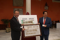 El delegado territorial de la ONCE y el presidente de Cajasol muestran a las cámaras la imagen del cupón dedicado a Cajasol