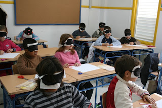 Un grupo de alumnos sentados en sus pupitres con los antifaces puestos