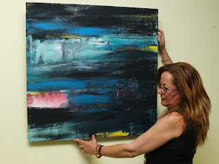 Pilar Lasierra sostiene uno de sus cuadros de paisajes marinos