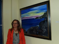 La pintora malagueña posa junto a uno de sus cuadros de paisajes marinos