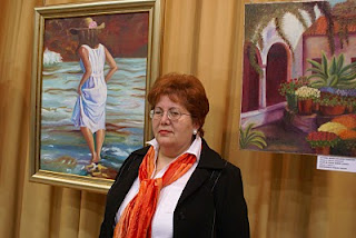 Mª Dolores Sánchez de Vides, pintora afiliada, posa junto a sus creaciones artísticas