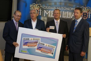 Foto de grupo con el cartel que contiene las imágenes de los cupones dedicados a las playas de Melilla. De izquierda a derecha, el director de la ONCE en Melilla, Juan Carlos Rubio, el presidente de la Ciudad Autónoma, Juan José Imbroda, el delegado de la ONCE de Andalucía, Ceuta y Melilla, Patricio Cárceles y el director de la ONCE en Málaga, Cristóbal Martínez