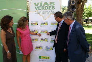 La consejera y el delegado de la ONCE señalando los cupones de las Vías Verdes