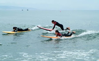 tres participantes tumados sobre la tabla sorteando las olas y disfrutando al máximo
