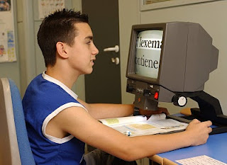 Un alumno frente a una lupa de aumento que le sirve de ayuda para estudiar