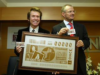 Raphael y Cárceles mostrando al público el cuadro con la imagen de la plancha que ha dado origen al cupón de Raphael