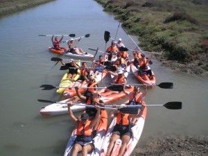 Los participantes del curso de piragüa posan sonrientes con los remos levantantados tras la competición