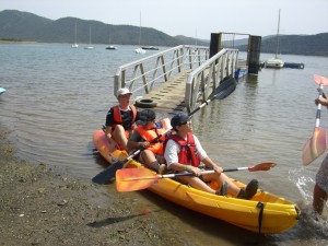 Tres jóvenes escuchan las pautas de los monitores antes de hacer piragüismo