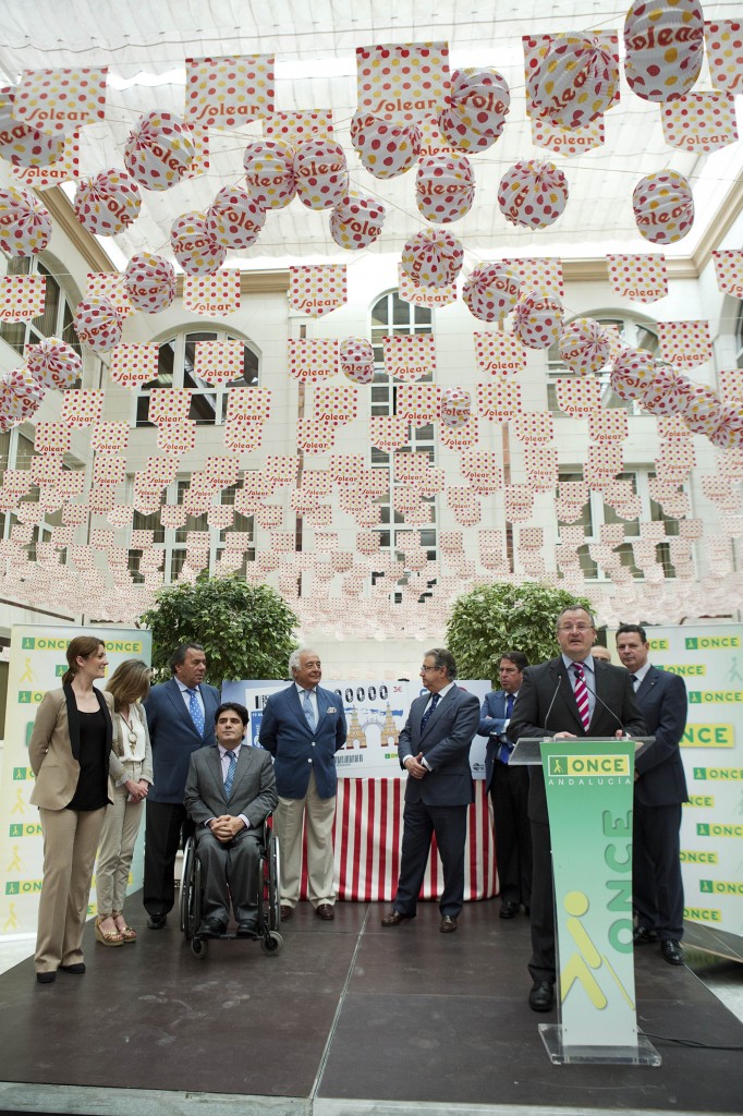 En la imagen, el delegado territorial de la ONCE en Andalucía, Ceuta y Melilla, Patricio Cárceles, pronuncia su discurso ante un escenario decorado como una caseta de Feria.